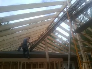 Rafters going up over a new addition with a worker on the wall in Fort Ogden