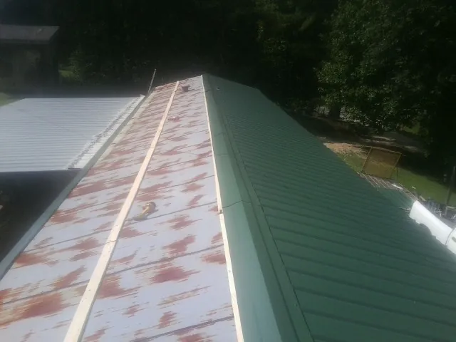 Old rusted panels beside newly installed green metal roofing — Wind Damage Roof Repair by Roofing Brothers in Fort Ogden