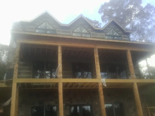 Dormers and porch framing on a large log home under construction — Roof Coating work by our crew in Fort Ogden