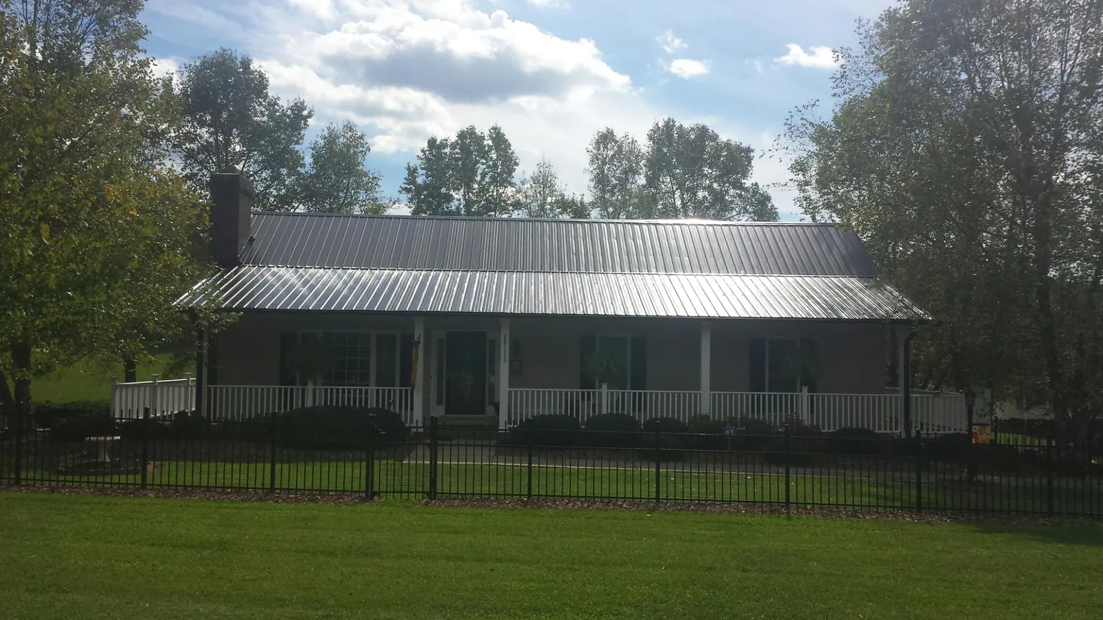 Gray metal roof on a brick ranch with a full width front porch — Gutter Guard Installation work by our crew in Fort Ogden