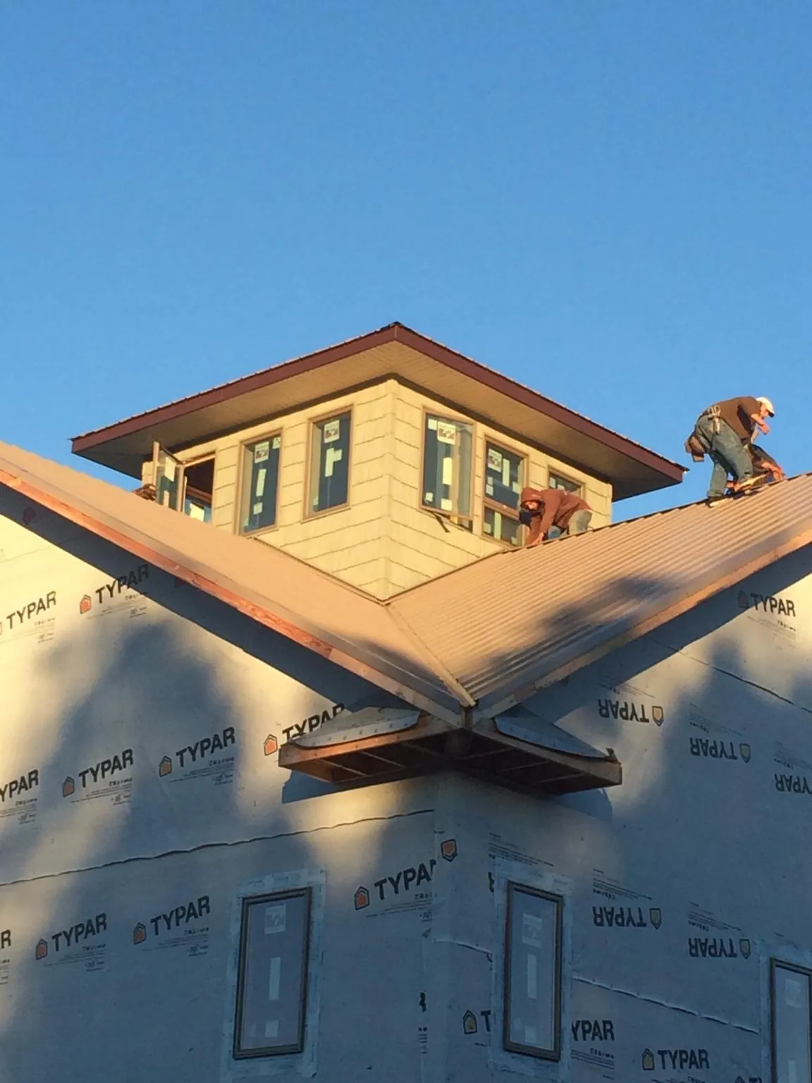 Roofers working around a rooftop cupola on a new metal roof at sunset — Roof Waterproofing in Fort Ogden by Roofing Brothers